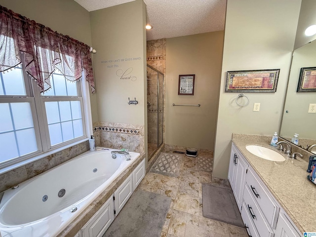 bathroom featuring independent shower and bath, vanity, and a textured ceiling