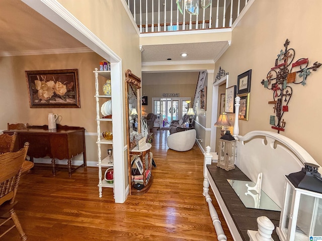 hall with hardwood / wood-style flooring, ornamental molding, and a high ceiling