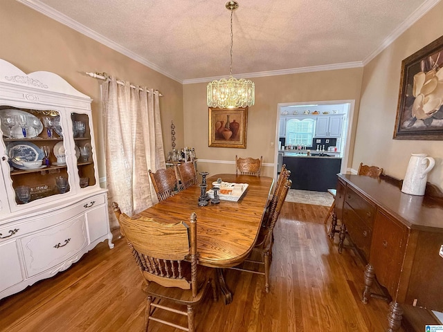 dining room with an inviting chandelier, hardwood / wood-style floors, crown molding, and a textured ceiling