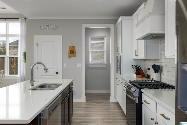 kitchen featuring sink, dishwasher, stainless steel range with gas stovetop, custom range hood, and white cabinets