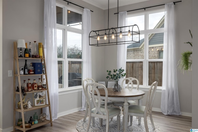 dining area with crown molding, light hardwood / wood-style flooring, and a notable chandelier