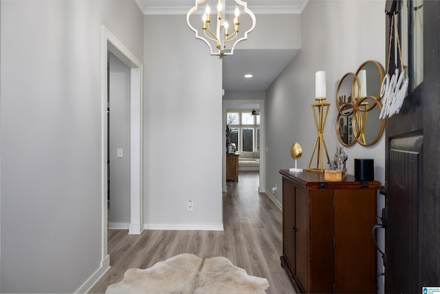 corridor with an inviting chandelier, ornamental molding, and light hardwood / wood-style flooring