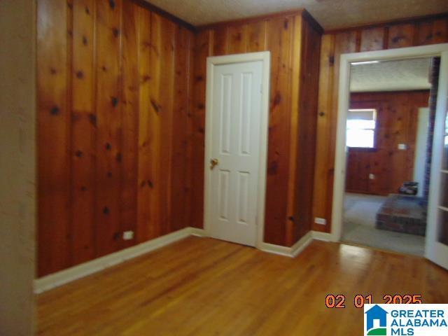 empty room with hardwood / wood-style flooring and wooden walls