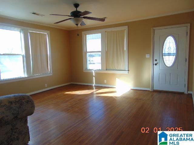 foyer featuring wood-type flooring, ornamental molding, and ceiling fan