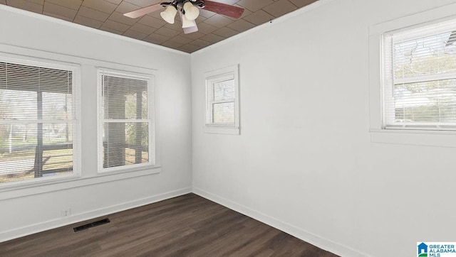 empty room with plenty of natural light, ornamental molding, dark hardwood / wood-style floors, and ceiling fan