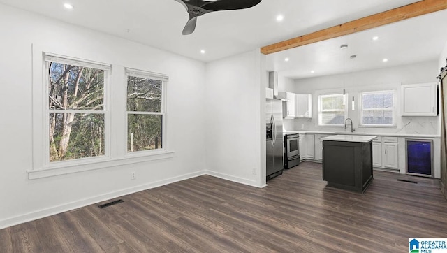 kitchen with wine cooler, sink, a kitchen island, and white cabinets