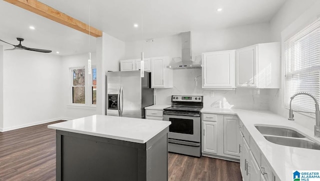 kitchen with a kitchen island, appliances with stainless steel finishes, sink, white cabinets, and wall chimney exhaust hood