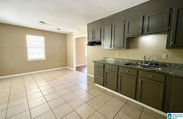 kitchen with light tile patterned flooring, sink, a textured ceiling, and dark stone counters