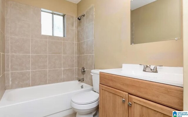 full bathroom featuring vanity, tiled shower / bath combo, and toilet