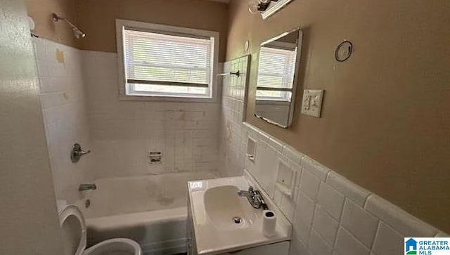 full bathroom featuring tile walls, sink, toilet, and tiled shower / bath