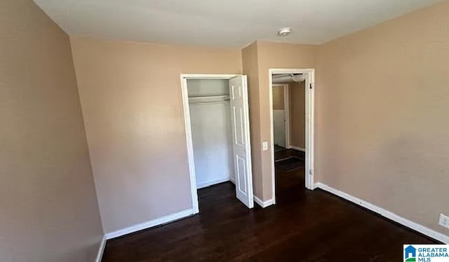 unfurnished bedroom with dark hardwood / wood-style floors and a closet