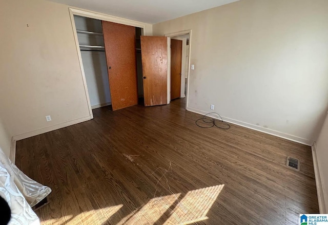 unfurnished bedroom featuring a closet and dark hardwood / wood-style floors