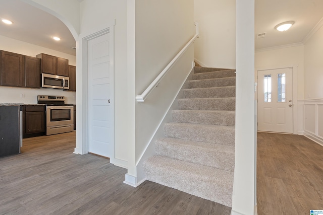 staircase featuring ornamental molding and hardwood / wood-style floors