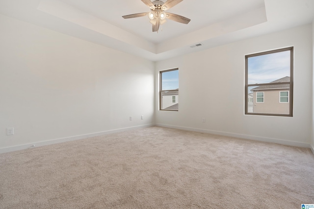 spare room with ceiling fan, carpet flooring, and a tray ceiling