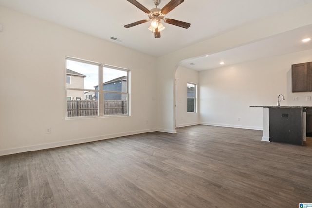 unfurnished living room with ceiling fan, sink, and dark hardwood / wood-style flooring