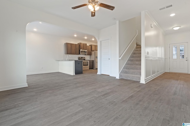 unfurnished living room featuring crown molding, ceiling fan, wood-type flooring, and sink