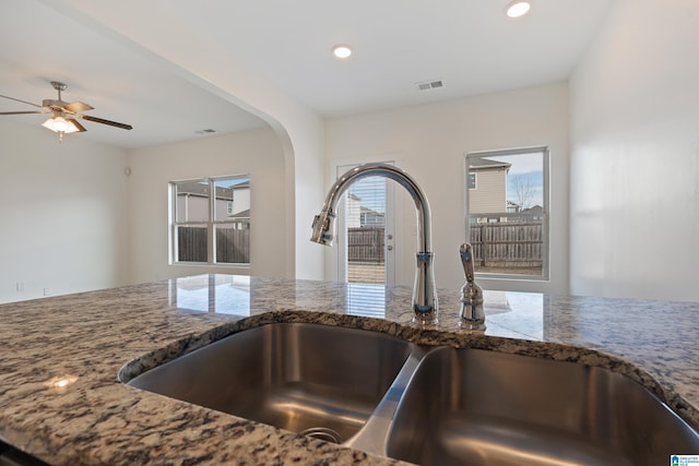 kitchen with dark stone countertops, sink, and ceiling fan