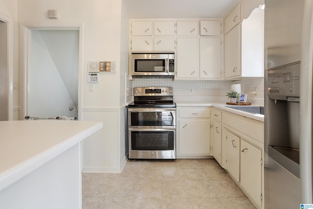 kitchen with light tile patterned flooring, appliances with stainless steel finishes, sink, decorative backsplash, and cream cabinets