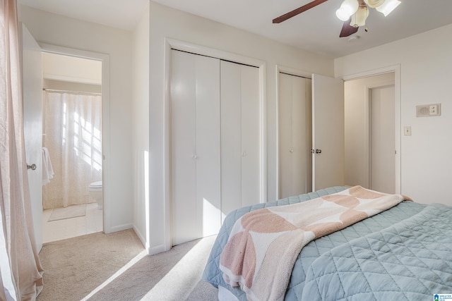 carpeted bedroom featuring multiple closets, ceiling fan, and ensuite bathroom