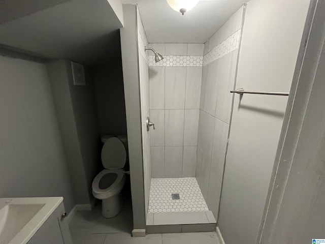 bathroom featuring tile patterned flooring, tiled shower, and toilet