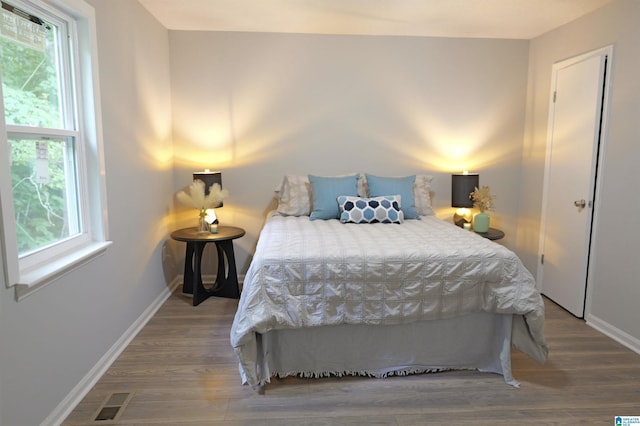 bedroom with hardwood / wood-style flooring and multiple windows