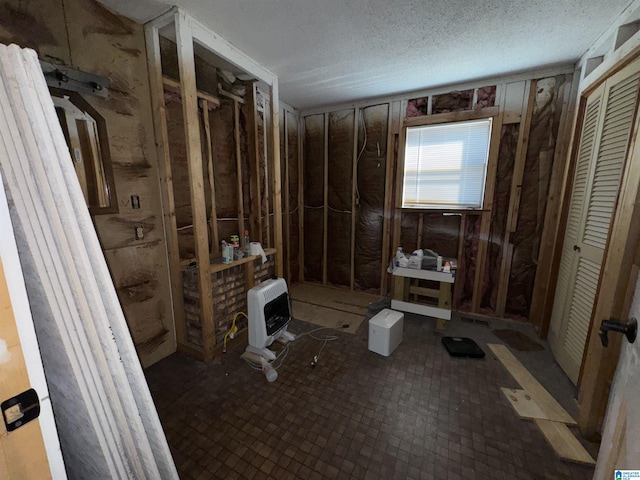 bathroom with heating unit and a textured ceiling