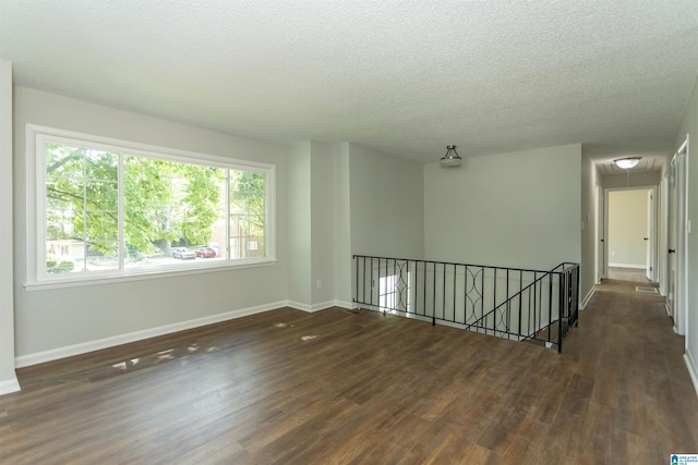 empty room featuring dark wood-type flooring and a textured ceiling