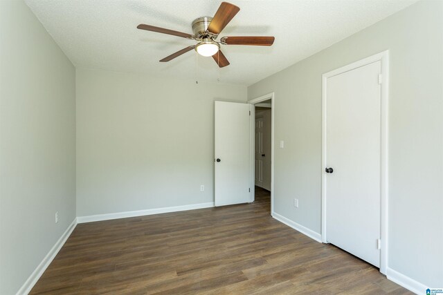 unfurnished bedroom with dark hardwood / wood-style floors, a textured ceiling, and ceiling fan