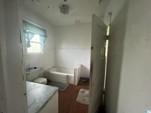 bathroom featuring a bathing tub, hardwood / wood-style floors, vanity, and toilet