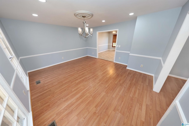 unfurnished room featuring an inviting chandelier and light hardwood / wood-style floors