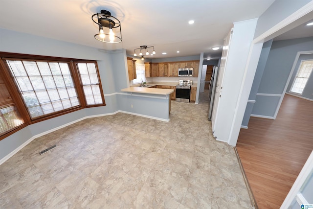 kitchen featuring appliances with stainless steel finishes, a breakfast bar, decorative light fixtures, sink, and kitchen peninsula