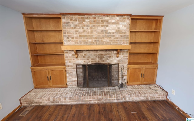 unfurnished living room featuring dark hardwood / wood-style flooring and a brick fireplace