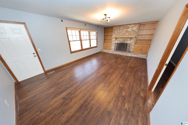 unfurnished living room with built in features, dark hardwood / wood-style flooring, and a brick fireplace