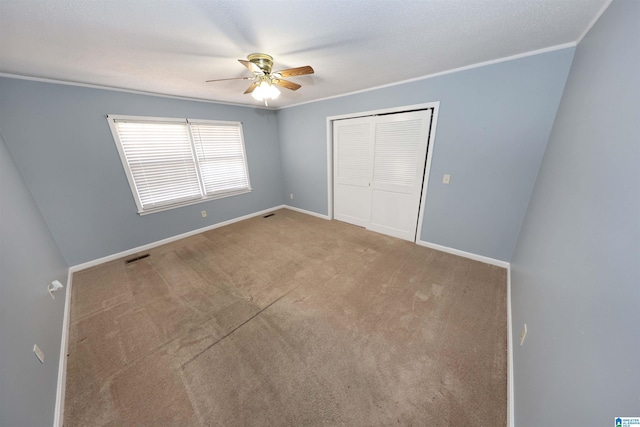 unfurnished bedroom with crown molding, light colored carpet, ceiling fan, and a closet