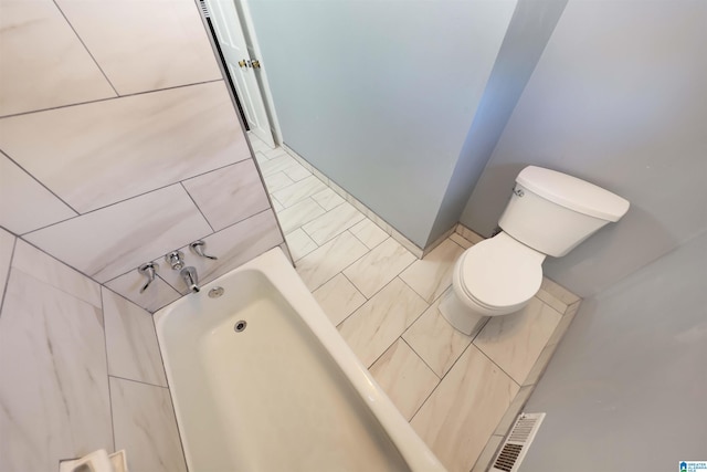 bathroom with tile patterned floors, toilet, and a washtub