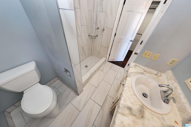 bathroom with vanity, toilet, and a tile shower