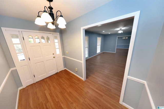 foyer with hardwood / wood-style flooring, a healthy amount of sunlight, and a notable chandelier