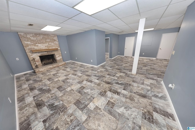 basement featuring a drop ceiling and a brick fireplace