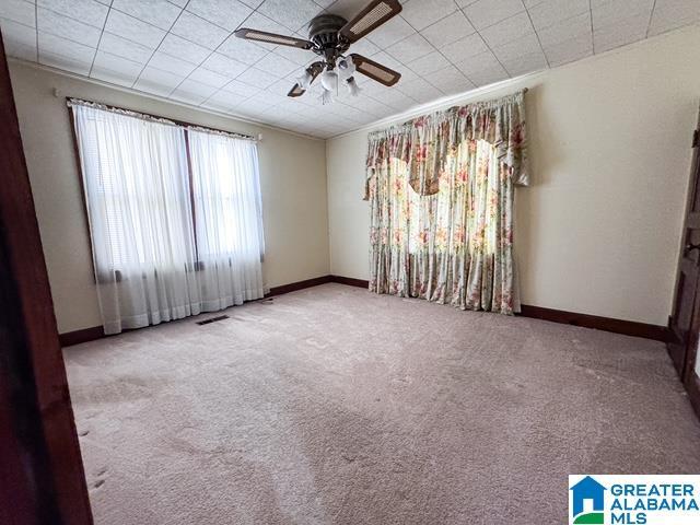 spare room with crown molding, carpet flooring, and ceiling fan