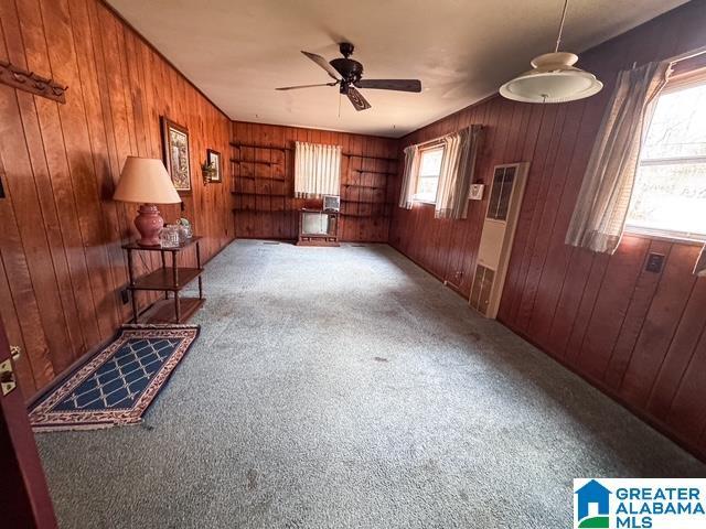 living room with ceiling fan, carpet, and wooden walls