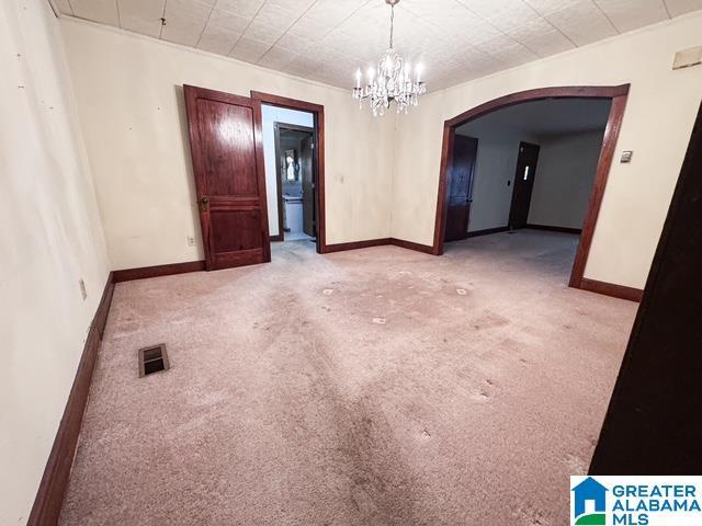 carpeted spare room with an inviting chandelier