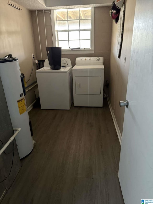 clothes washing area featuring dark wood-type flooring, electric water heater, and washing machine and dryer