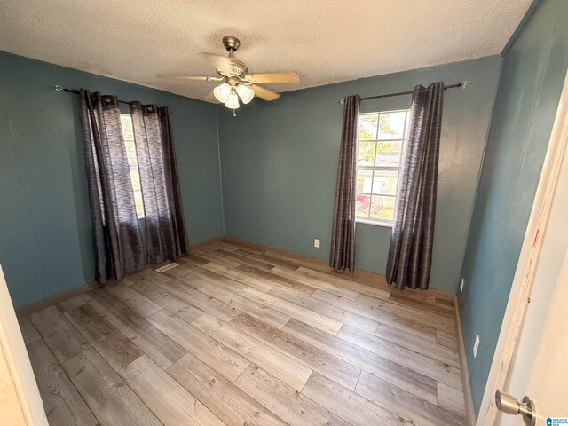 spare room with ceiling fan, light hardwood / wood-style flooring, and a textured ceiling