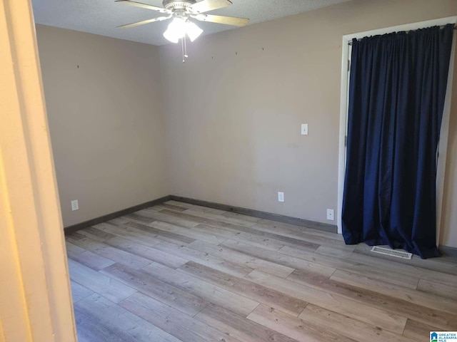 empty room with ceiling fan, a textured ceiling, and light wood-type flooring