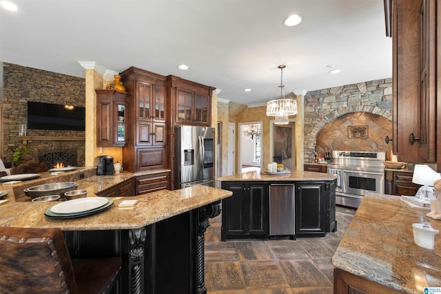 kitchen with appliances with stainless steel finishes, a stone fireplace, pendant lighting, a kitchen bar, and a center island