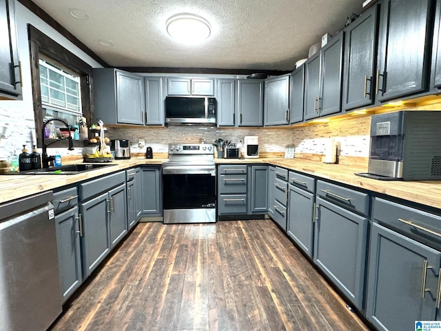 kitchen with dark wood-type flooring, sink, gray cabinets, stainless steel appliances, and backsplash