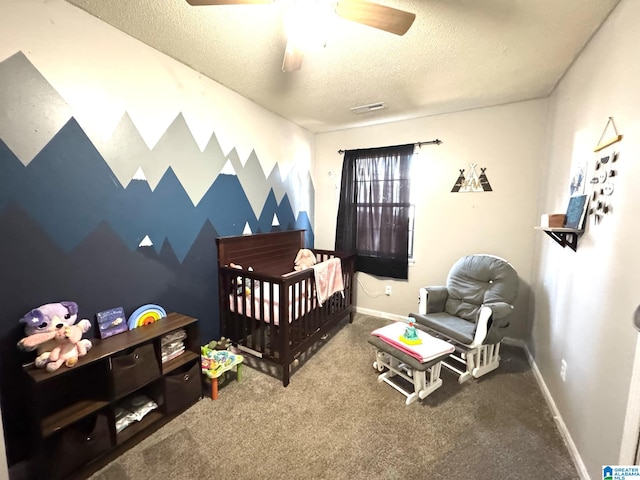 bedroom with ceiling fan, a nursery area, carpet floors, and a textured ceiling