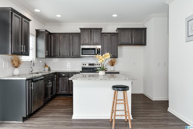 kitchen featuring light stone counters, stainless steel appliances, sink, and a kitchen island