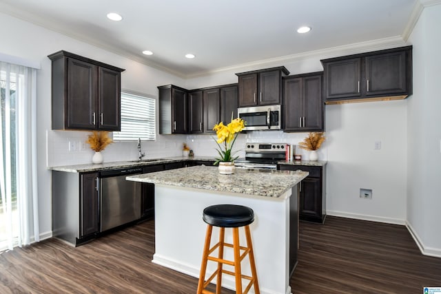 kitchen featuring a kitchen island, dark hardwood / wood-style floors, sink, stainless steel appliances, and light stone countertops