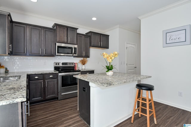 kitchen featuring appliances with stainless steel finishes, backsplash, dark hardwood / wood-style floors, a center island, and ornamental molding